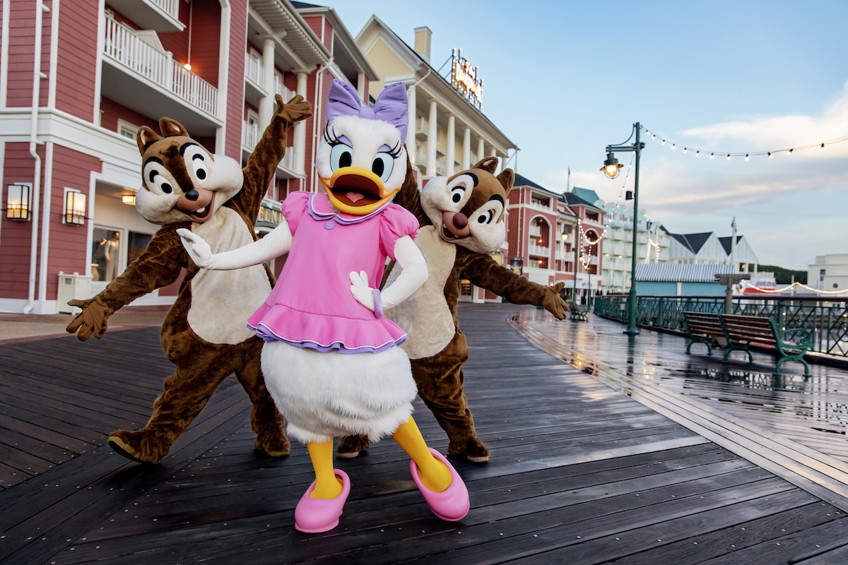 A smiling mother and two young children happily walk around Disney's Grand Floridian Resort & Spa.