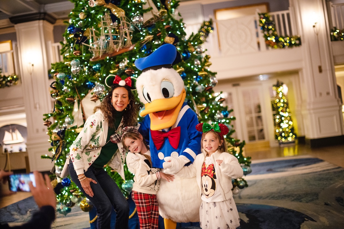 A smiling mother and two young children happily walk around Disney's Grand Floridian Resort & Spa.
