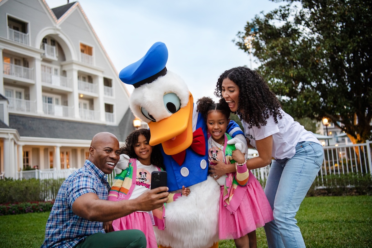 A smiling mother and two young children happily walk around Disney's Grand Floridian Resort & Spa.