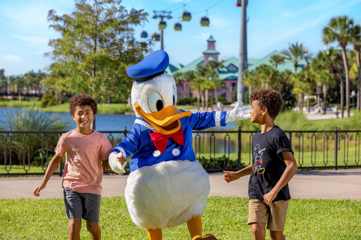 A smiling mother and two young children happily walk around Disney's Grand Floridian Resort & Spa.
